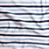 Close up of gently draped striped woven Indoor-Outdoor fabric in white, light blue navy and dark blue. 
