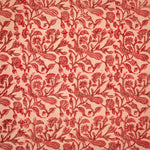 Detail of fabric in a dense peacock and floral print in red and brown on a pink field.