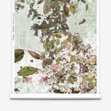 Roll of floral wallpaper with green leaves and pink flowers on a light background