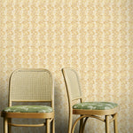 Two wooden chairs with green cushions against a yellow floral wallpapered wall.