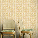 Two wooden chairs with green cushions against a yellow floral wallpapered wall.