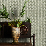 Decorative green floral wallpaper with a subtle pattern, potted plant on a wooden cabinet.