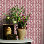 Decorative table with vase of flowers and owl figurine against a wine floral patterned wall.