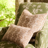 Floral-patterned cushions on a green upholstered chair with a blurred outdoor background