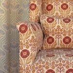 Detail of an upholstered chair in a floral pattern in orange and red on cream