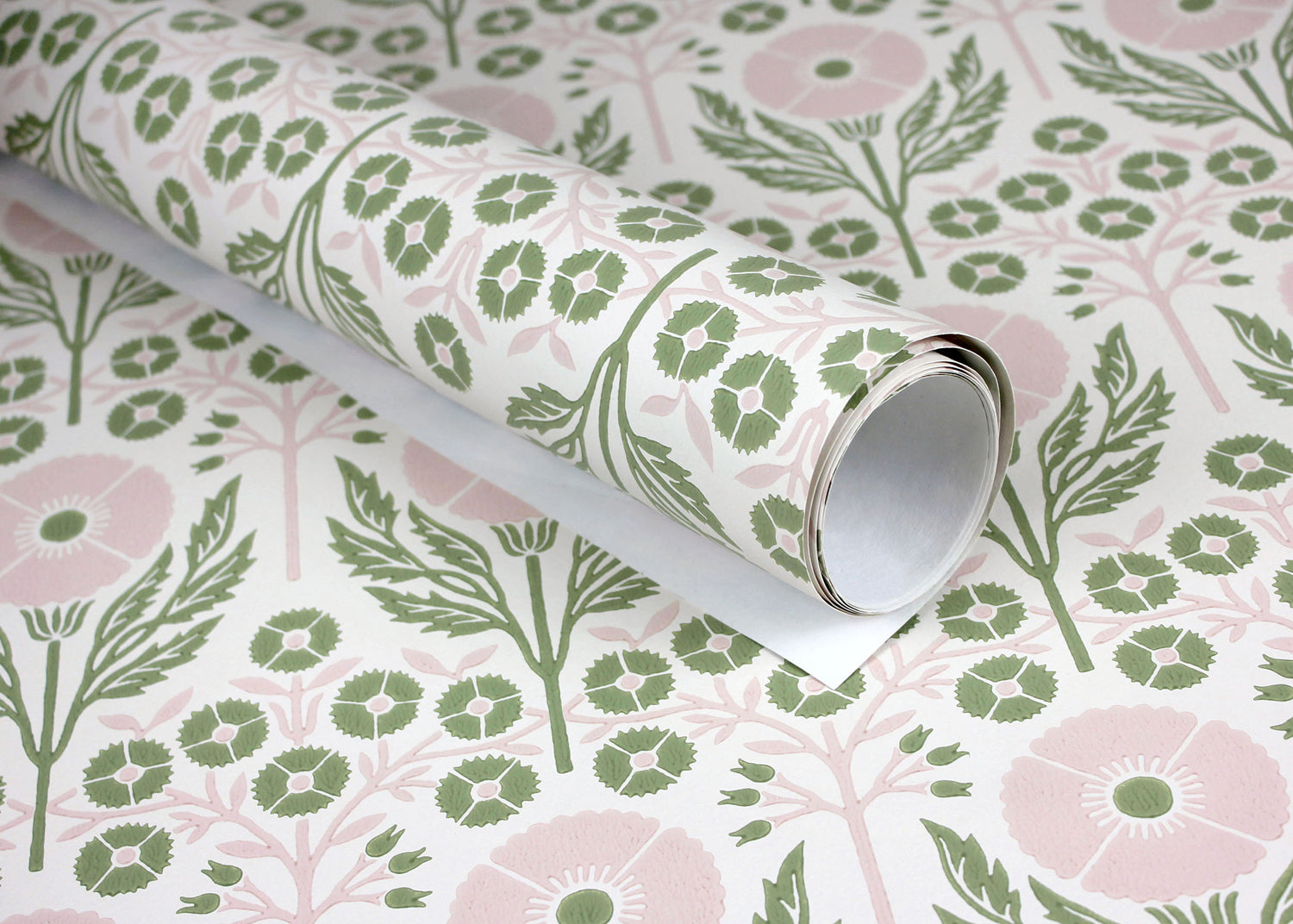 Wallpaper roll in an arts and crafts style floral pattern in pink and green on white. 