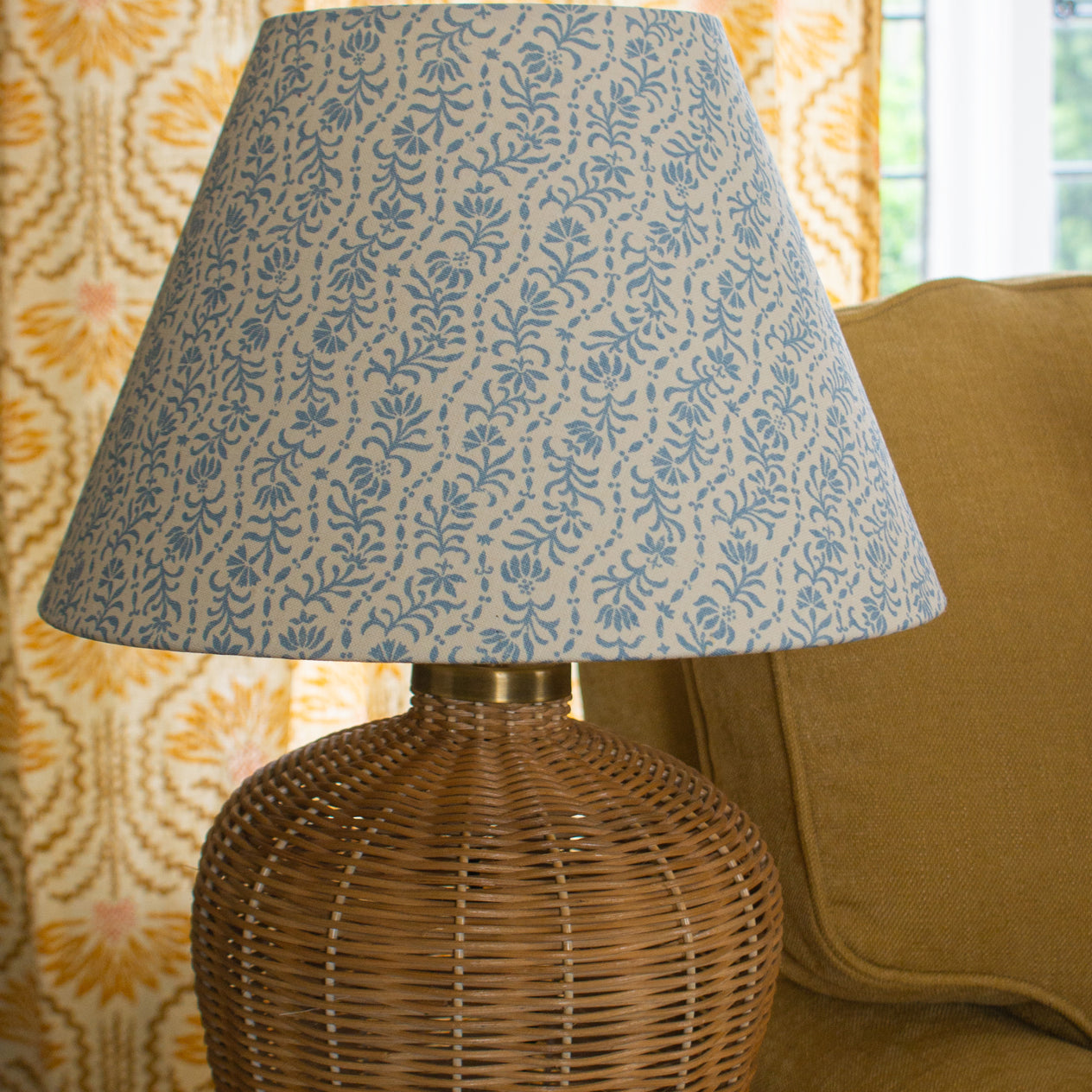 Rattan table lamp with a blue and white floral stripe shade. 