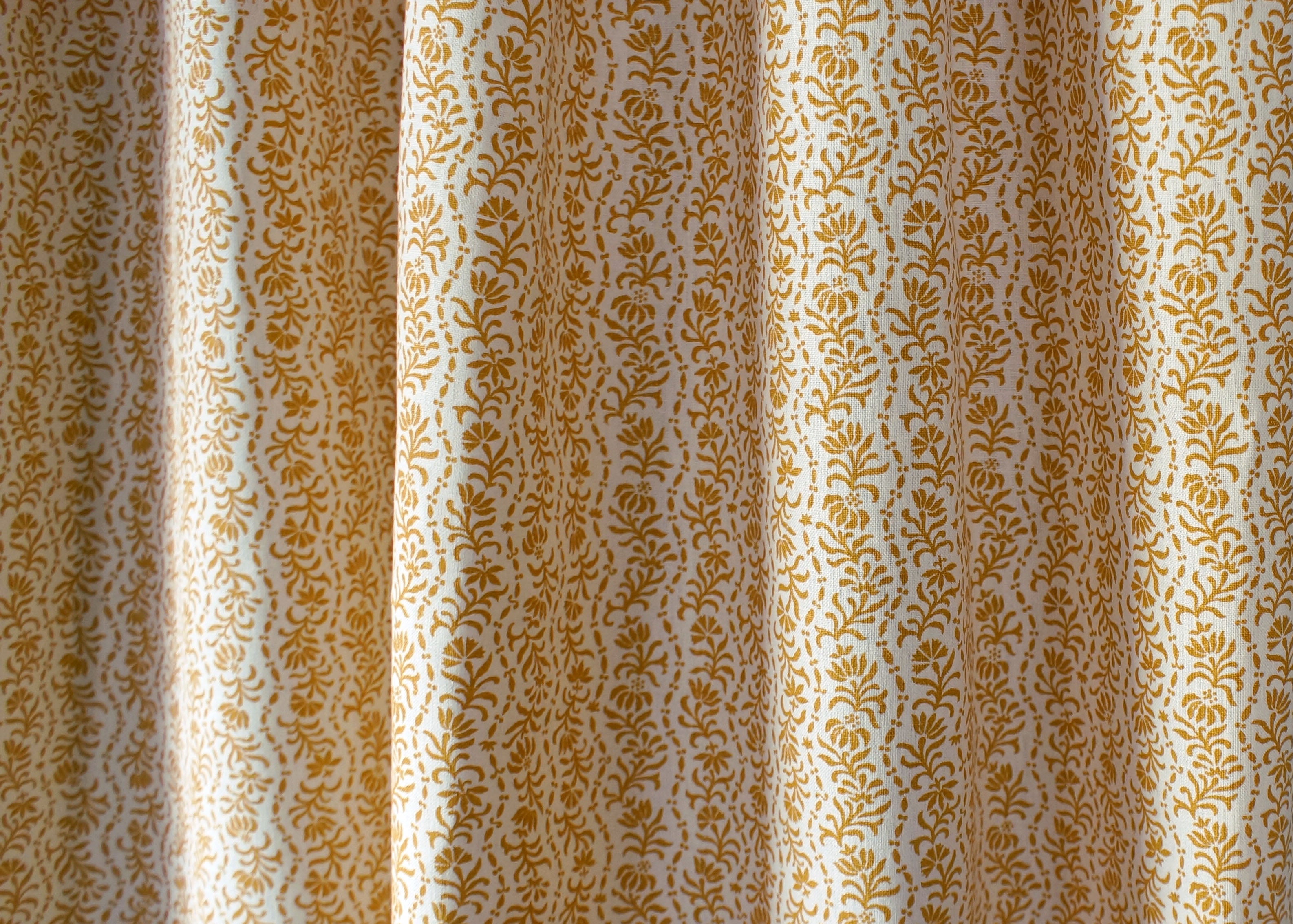 Drapped printed linen in a wavy floral stripe design in yellow on cream.