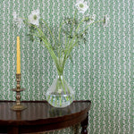 Ornate settee in a wavy floral stripe design in green on white against wallpaper in the same design. 