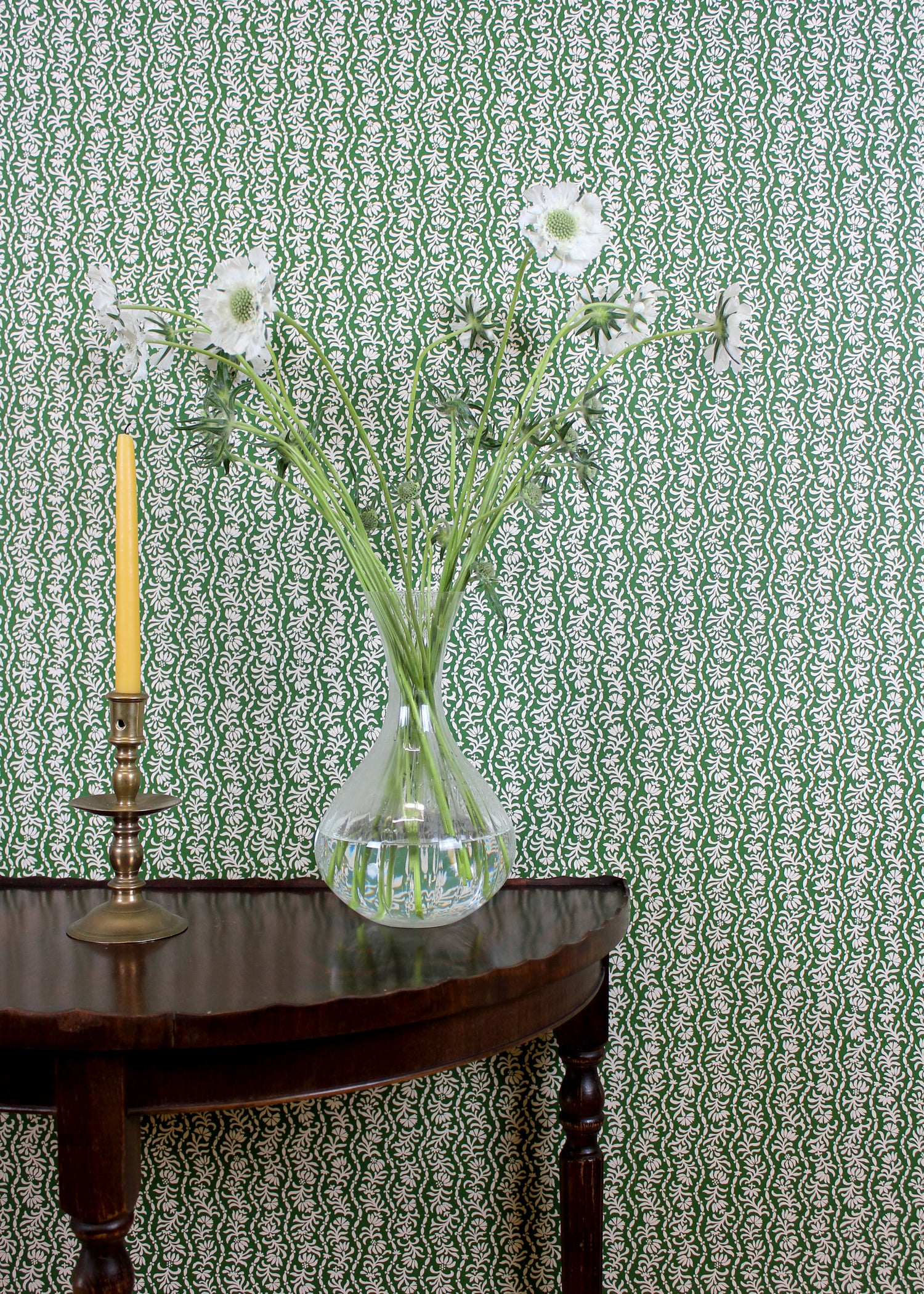 Ornate settee in a wavy floral stripe design in green on white against wallpaper in the same design. 
