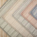 Stack of broadloom carpet samples in a textural herringbone design in a range of colors. 
