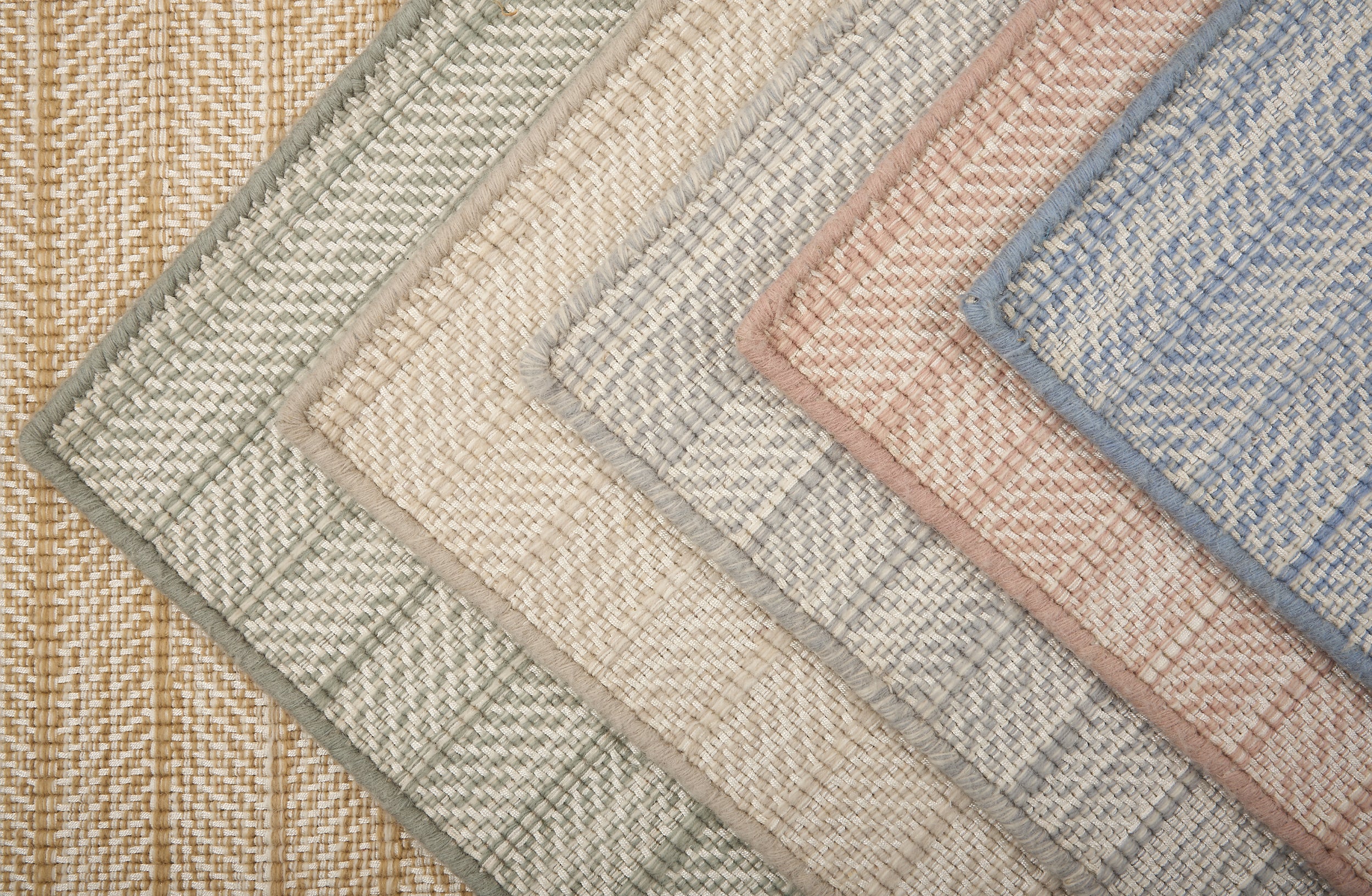 Stack of broadloom carpet samples in a textural herringbone design in a range of colors. 