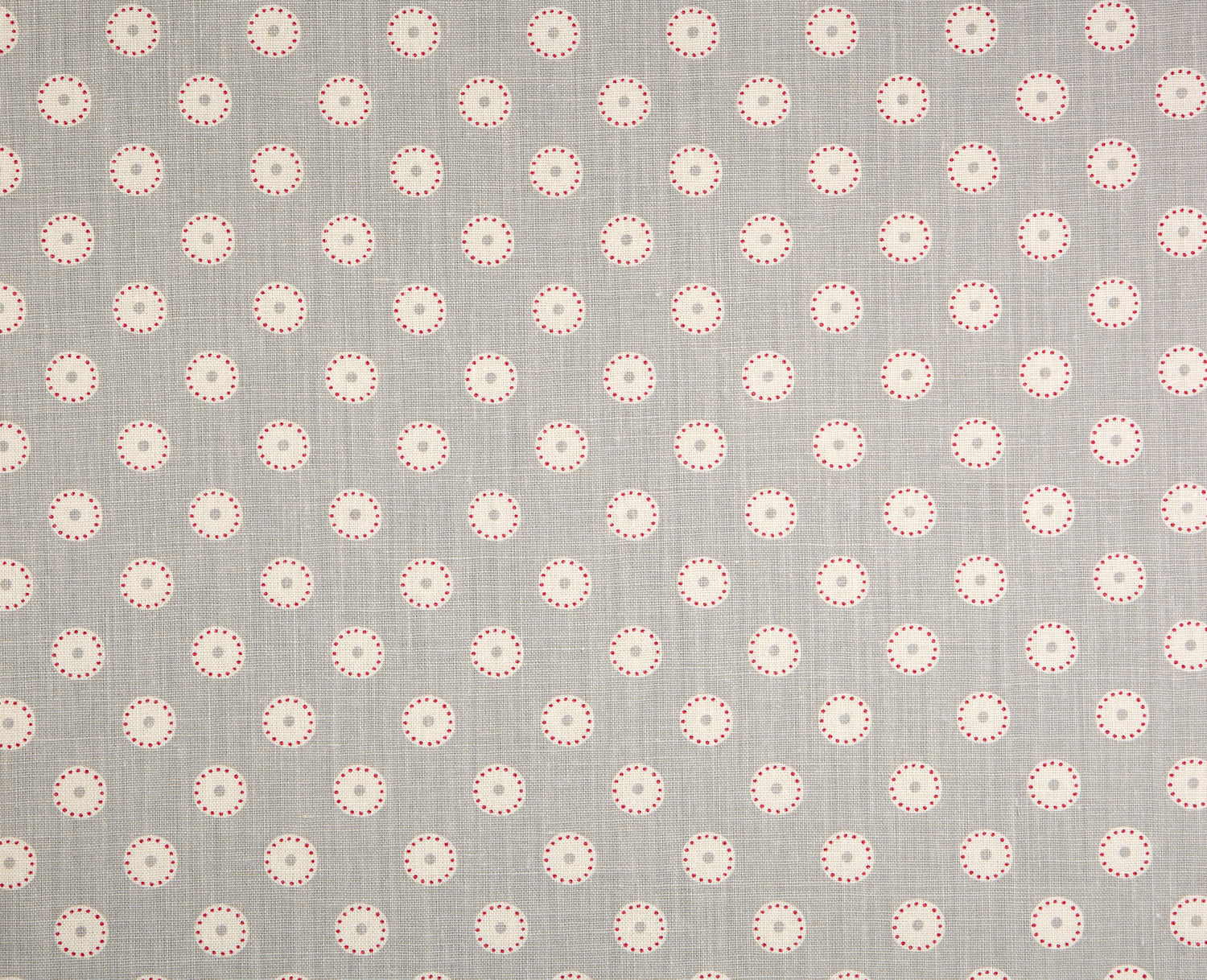 Detail of fabric in a playful dot print in pink and cream on a gray field.