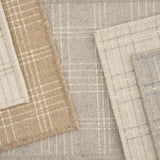 Stack of broadloom carpets in a windowpane plaid pattern in various light neutral colors. 