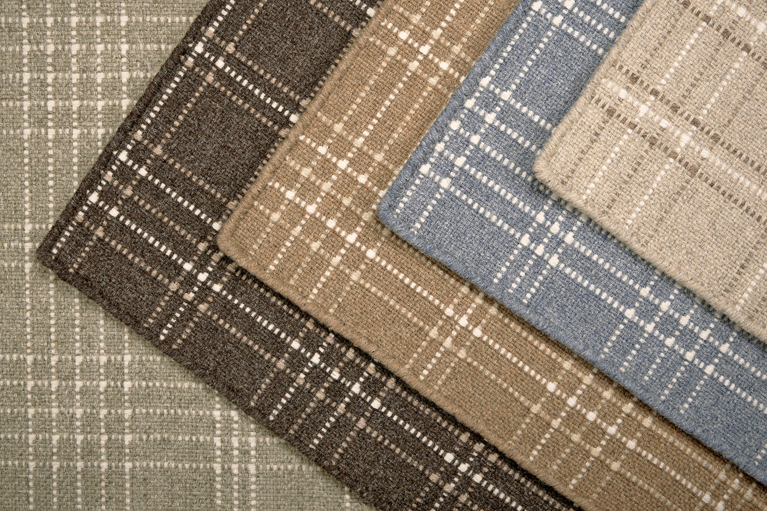 Stack of windowpane plaid broadloom carpets in various colors. 