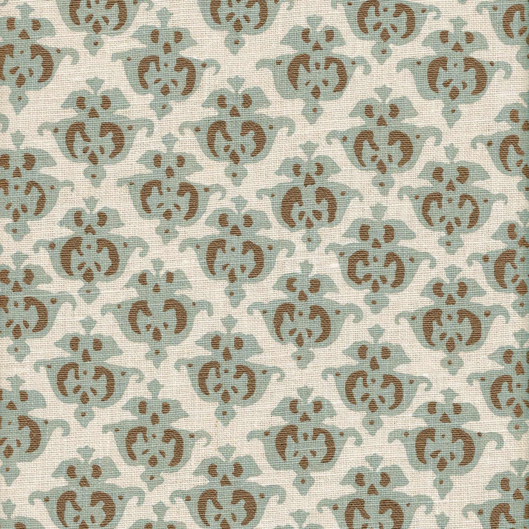 Detail of fabric in a repeating damask print in blue and brown on a cream field.