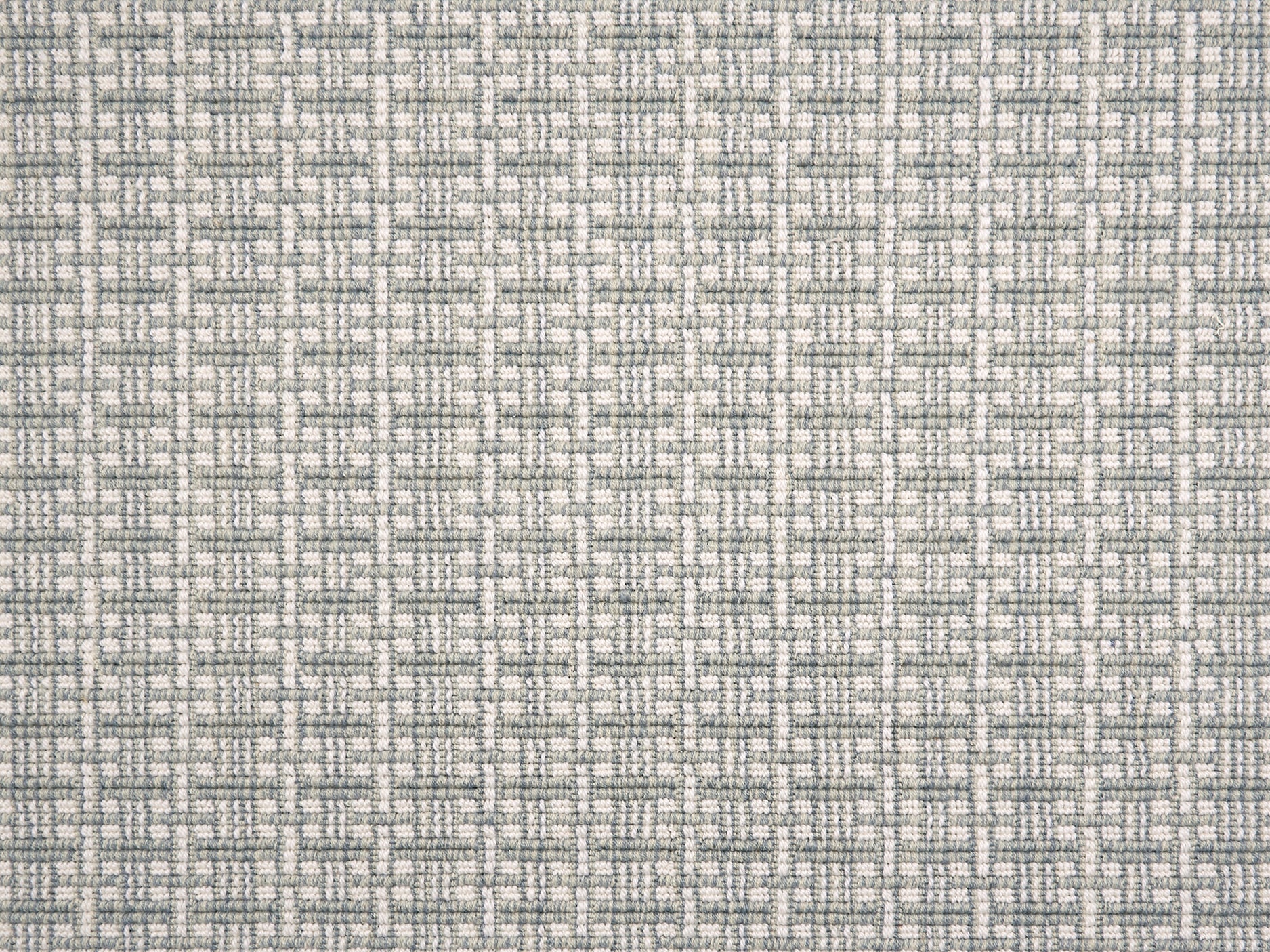 A close-up of broadloom carpet with a textured basketweave pattern in warm cream and sky blue.