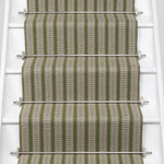 White stair case with a complex woven striped runner made of wool in shades of green with grey and red accents.