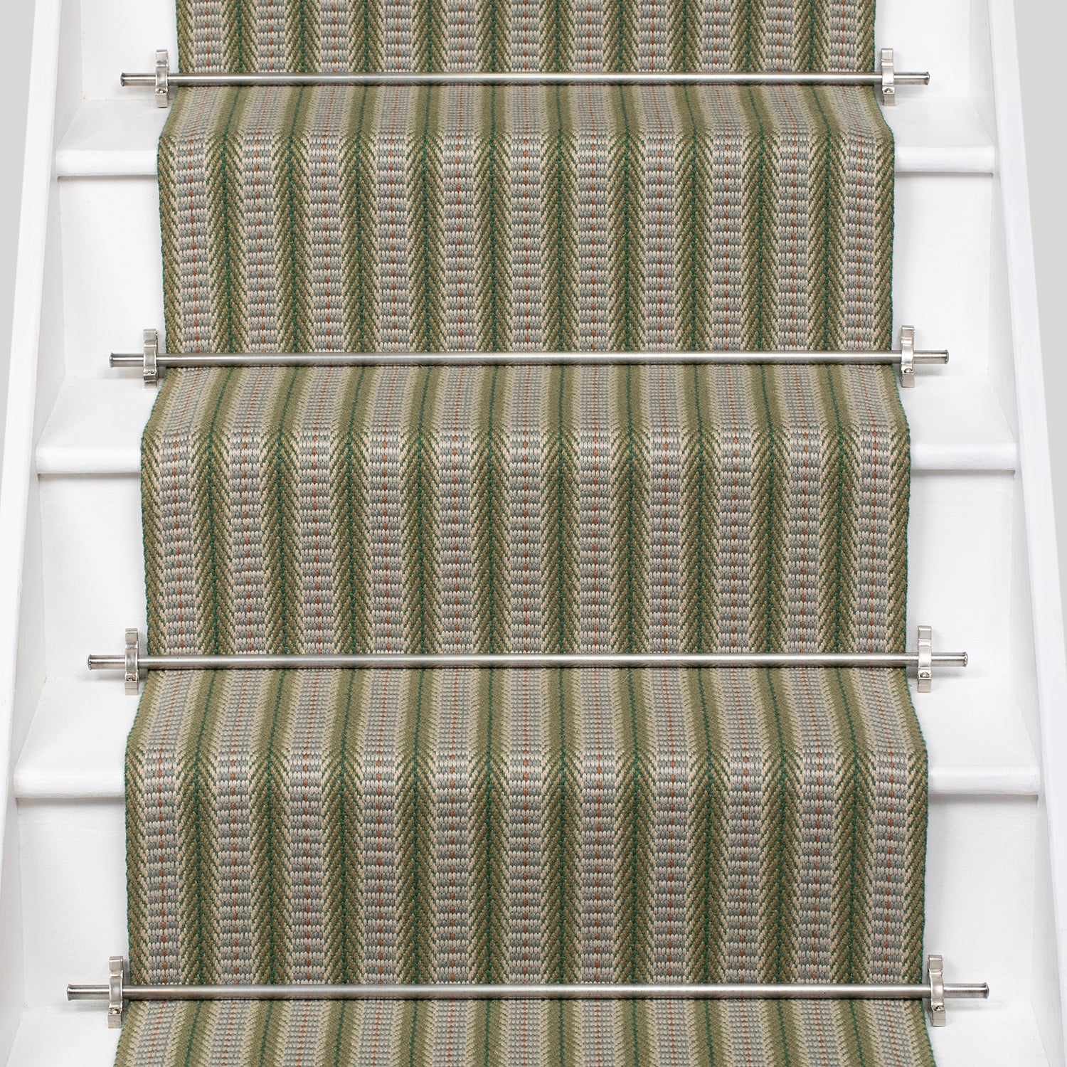 White stair case with a complex woven striped runner made of wool in shades of green with grey and red accents.