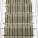 White stair case with a complex woven striped runner made of wool in shades of green with grey and red accents.