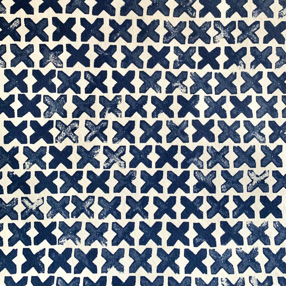 Detail of wallpaper in a repeating "X" print in indigo on a cream field.