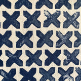 Close-up of wallpaper in a repeating "X" print in indigo on a cream field.