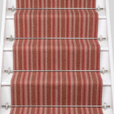 White staircase with a runner in a complex woven striped runner made of wool in shades of red.