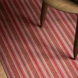 Detail of an area rug in a complex woven striped runner made of wool in shades of red.