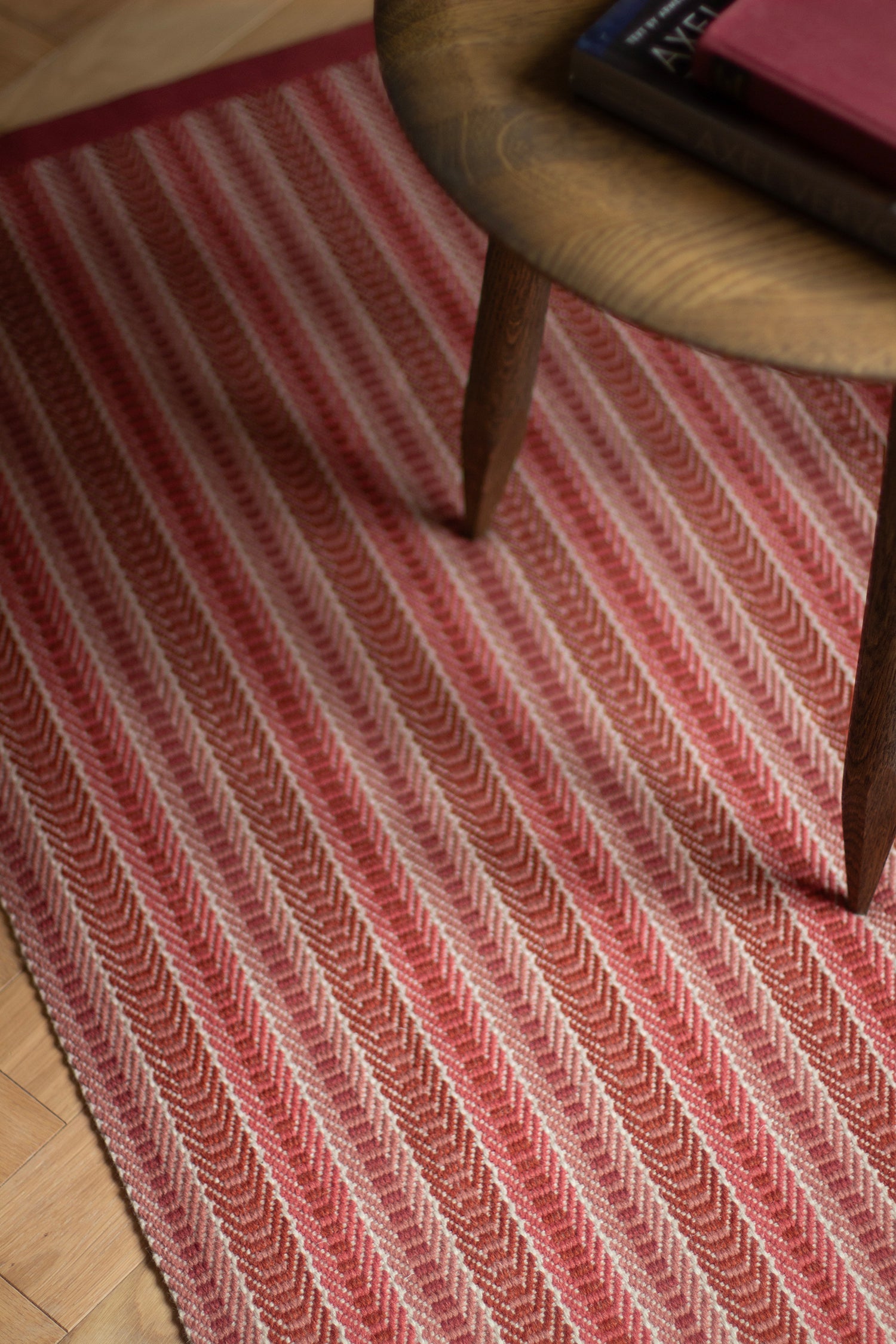 Detail of an area rug in a complex woven striped runner made of wool in shades of red.