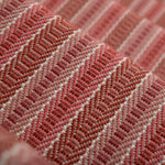Detail of a stair runner in a complex woven striped runner made of wool in shades of red.