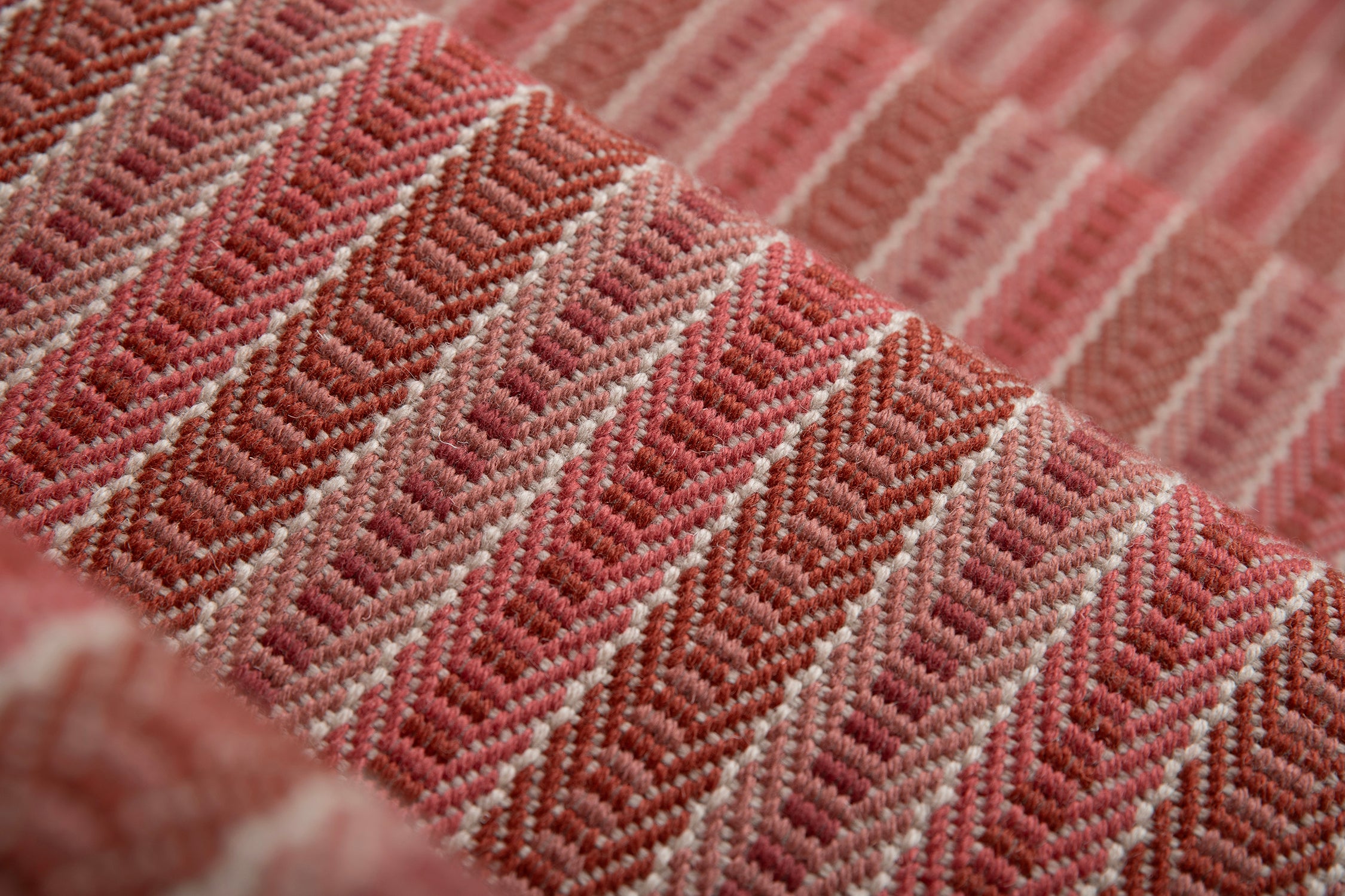 Detail of a stair runner in a complex woven striped runner made of wool in shades of red.