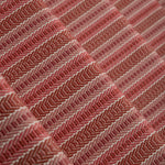 Detail of a stair runner in a complex woven striped runner made of wool in shades of red.