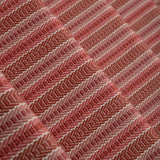 Detail of a stair runner in a complex woven striped runner made of wool in shades of red.