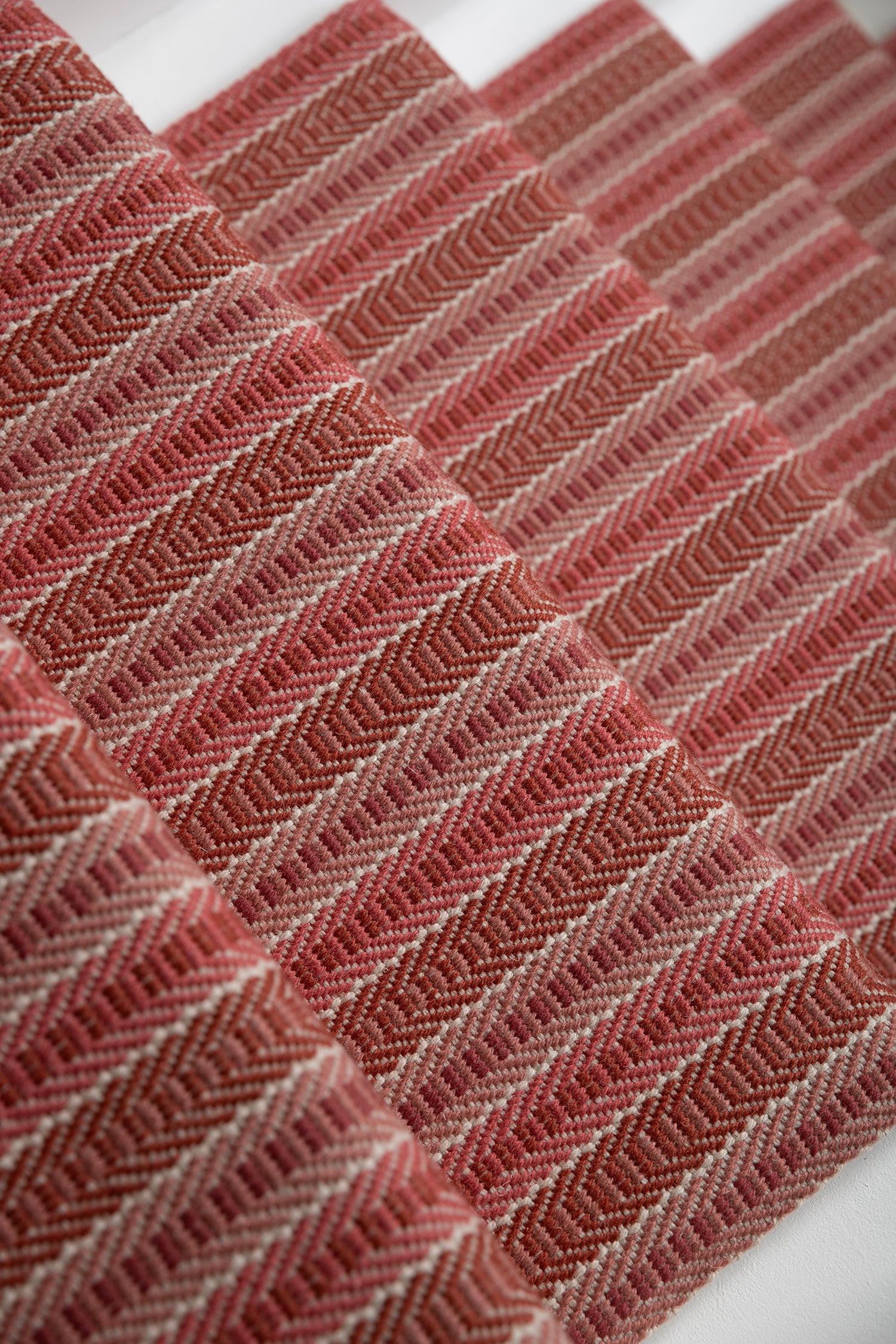 Detail of a stair runner in a complex woven striped runner made of wool in shades of red.