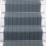 A close-up view of a staircase with carpeted steps in a blue-gray stripe pattern, bordered by white risers,