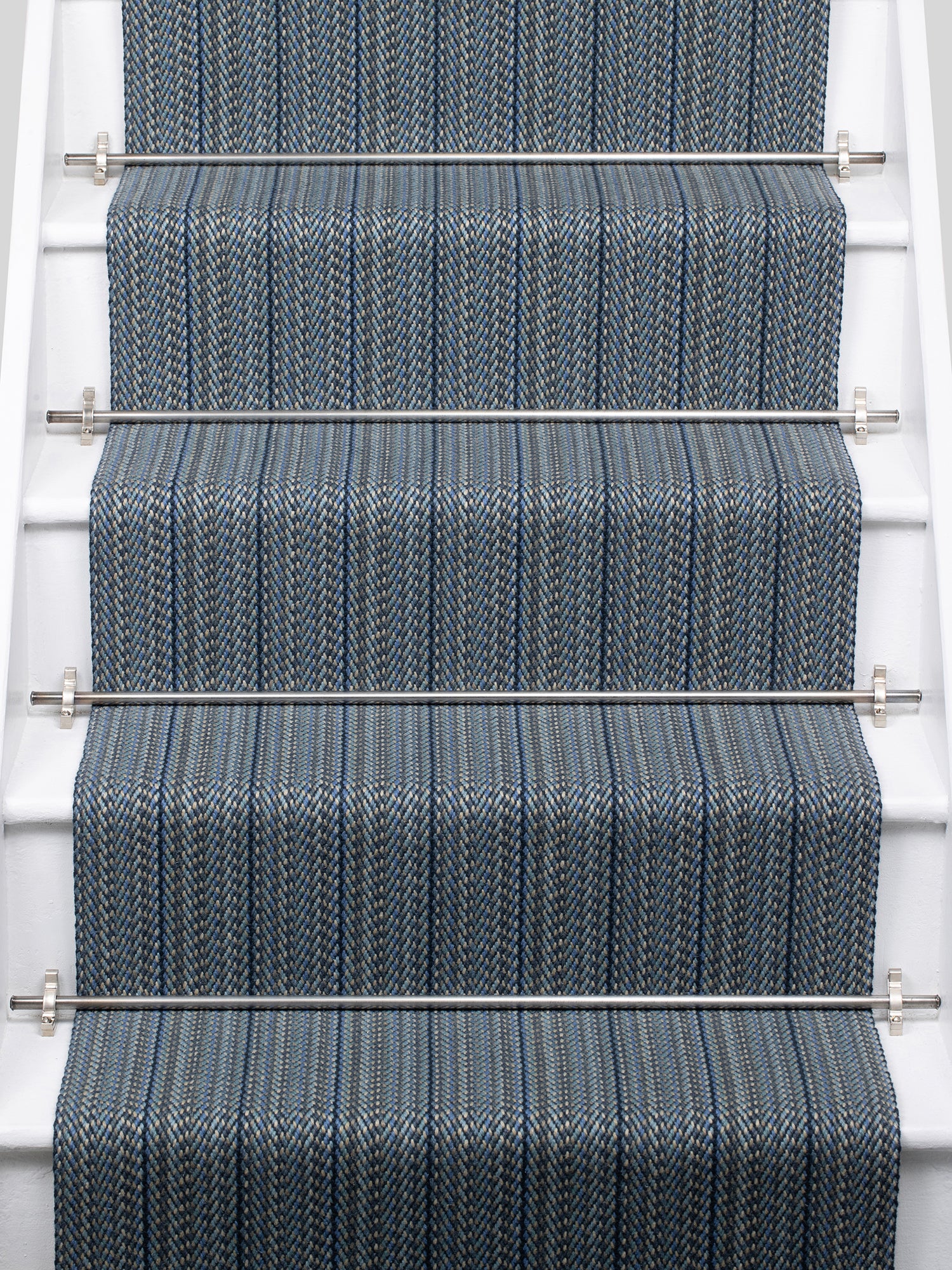 A close-up view of a staircase with carpeted steps in a blue-gray stripe pattern, bordered by white risers,