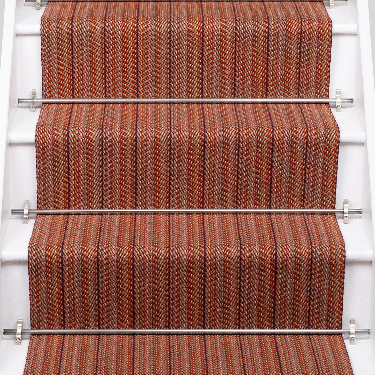 A close-up view of a staircase with carpeted steps in a red-orange stripe pattern, bordered by white risers.