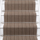 A close-up view of a staircase with carpeted steps in a taupe-brown stripe pattern, bordered by white risers