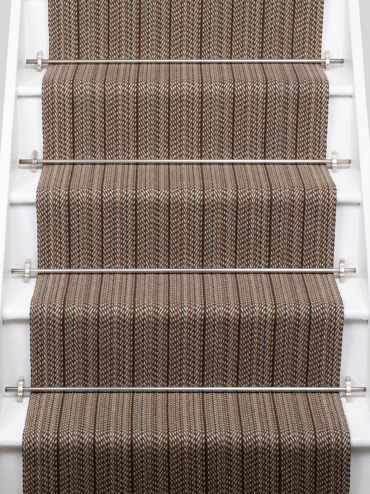 A close-up view of a staircase with carpeted steps in a taupe-brown stripe pattern, bordered by white risers