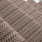 A close-up of a stair runner with a textured stripe in mixed brown, beige, and gray tones.