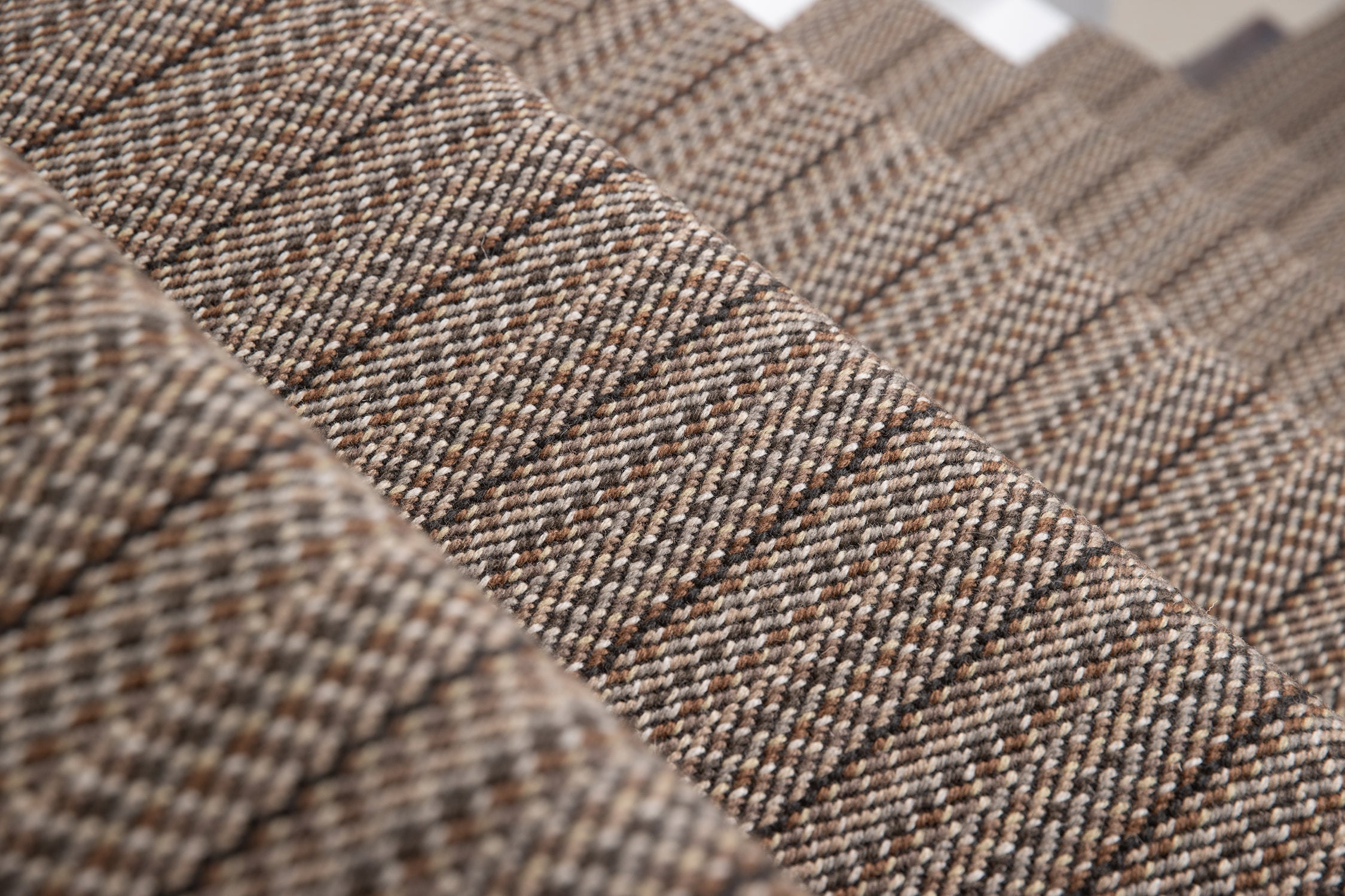 A close-up of a stair runner with a textured stripe in mixed brown, beige, and gray tones.