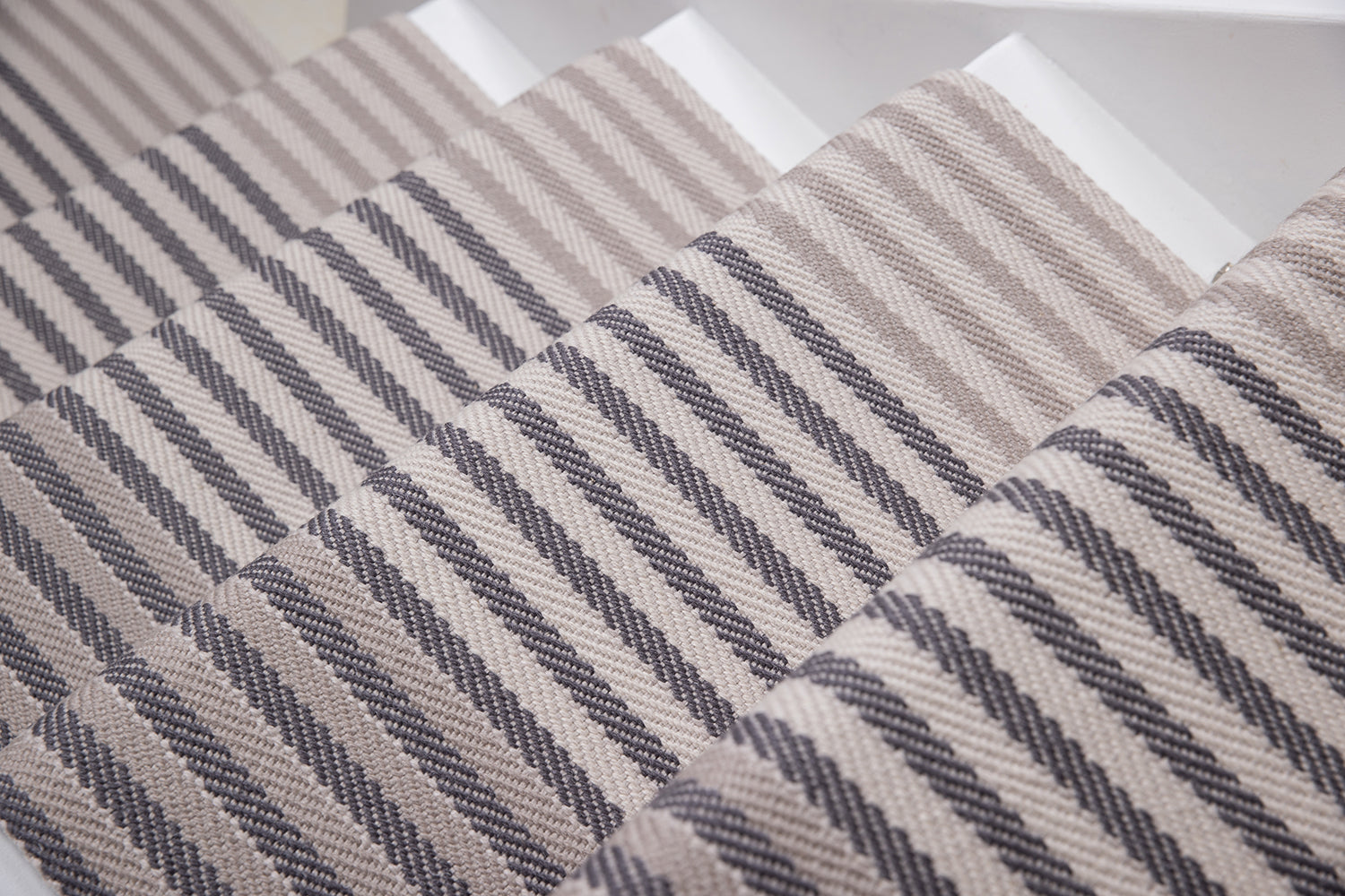 Close-up of a flatweave stair runner striped pattern in beige, taupe, and dark gray.