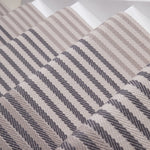 Close-up of a flatweave stair runner striped pattern in beige, taupe, and dark gray.
