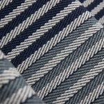 Close-up of a stair runner with a diagonal herringbone stripe in navy blue, steel blue and grey.