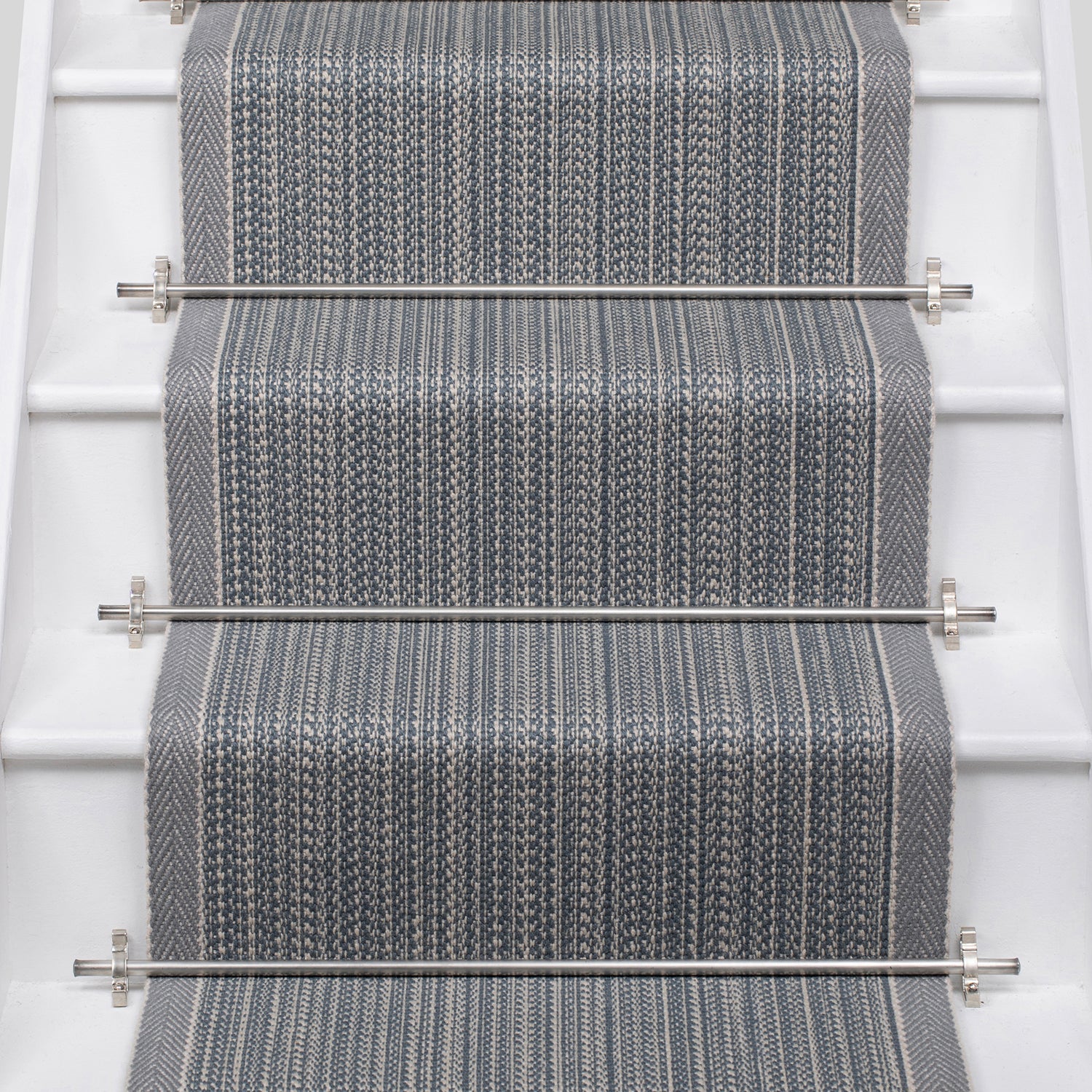 White stairs with textural striped runner in slate gray and blue with metal stair rails. 
