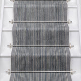 White stairs with textural striped runner in slate gray and blue with metal stair rails. 