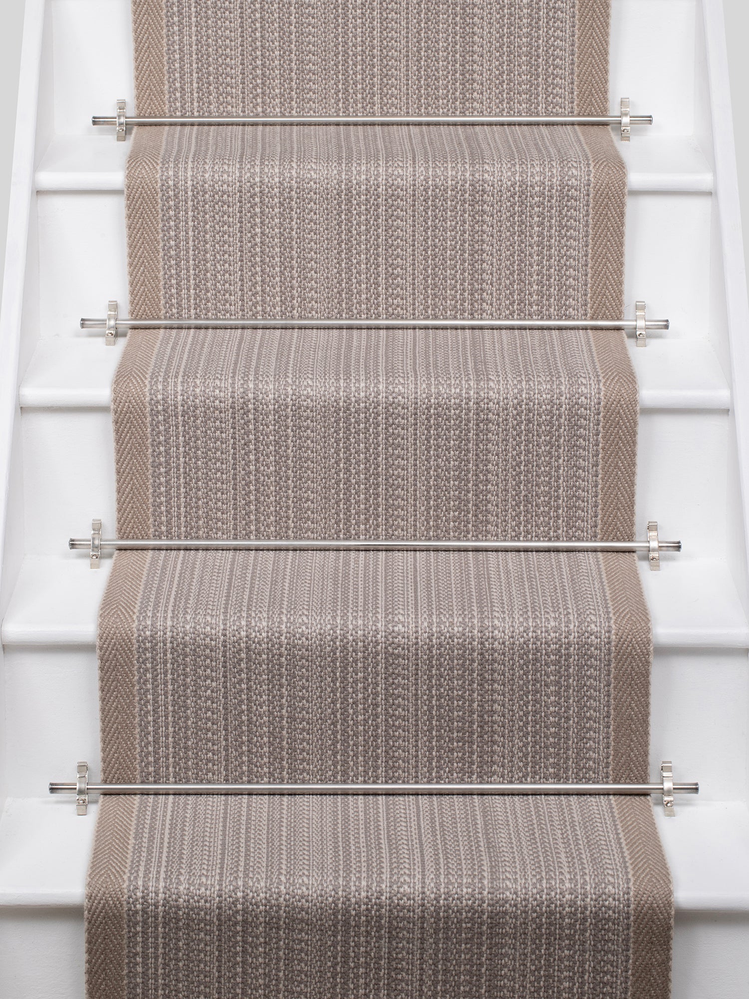 White stairs with textural striped runner in warm beige with metal stair rails. 