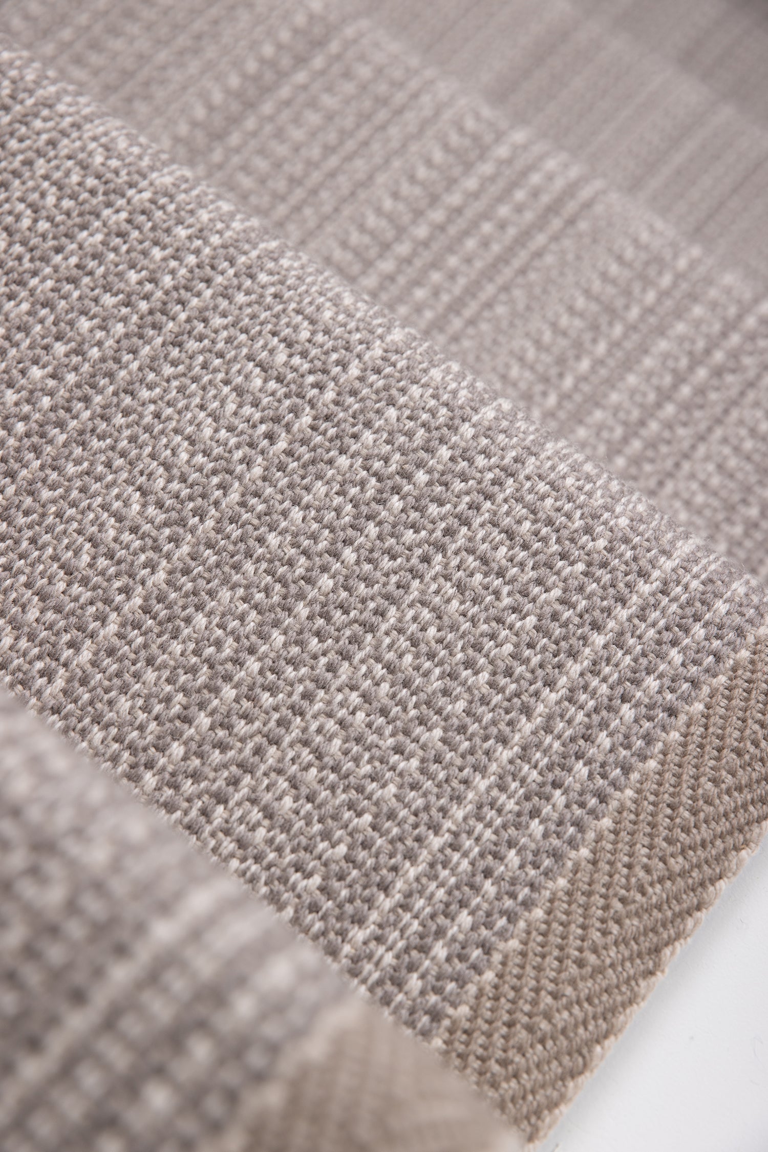 Close-up of flatweave stair runner in a light taupe-beige color, showing the detailed weave and a folded edge.