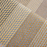 A close-up of a woven stair runner with a herringbone pattern in mustard yellow, light gray, and dark charcoal.