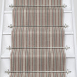 White stair case with a runner in a complex woven stripe design of wool in shades of pink and grey.